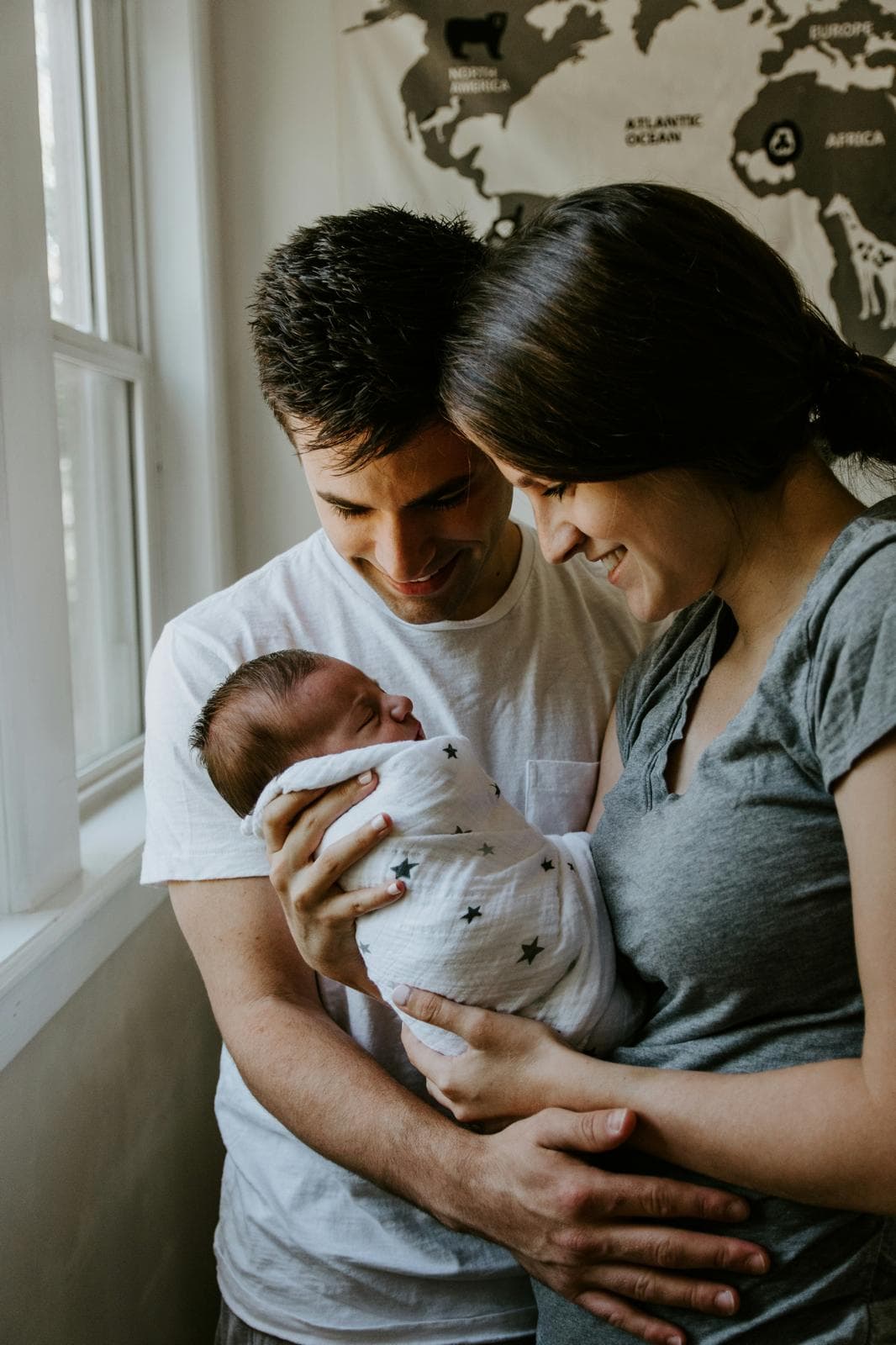 A couple by a window holding their newborn