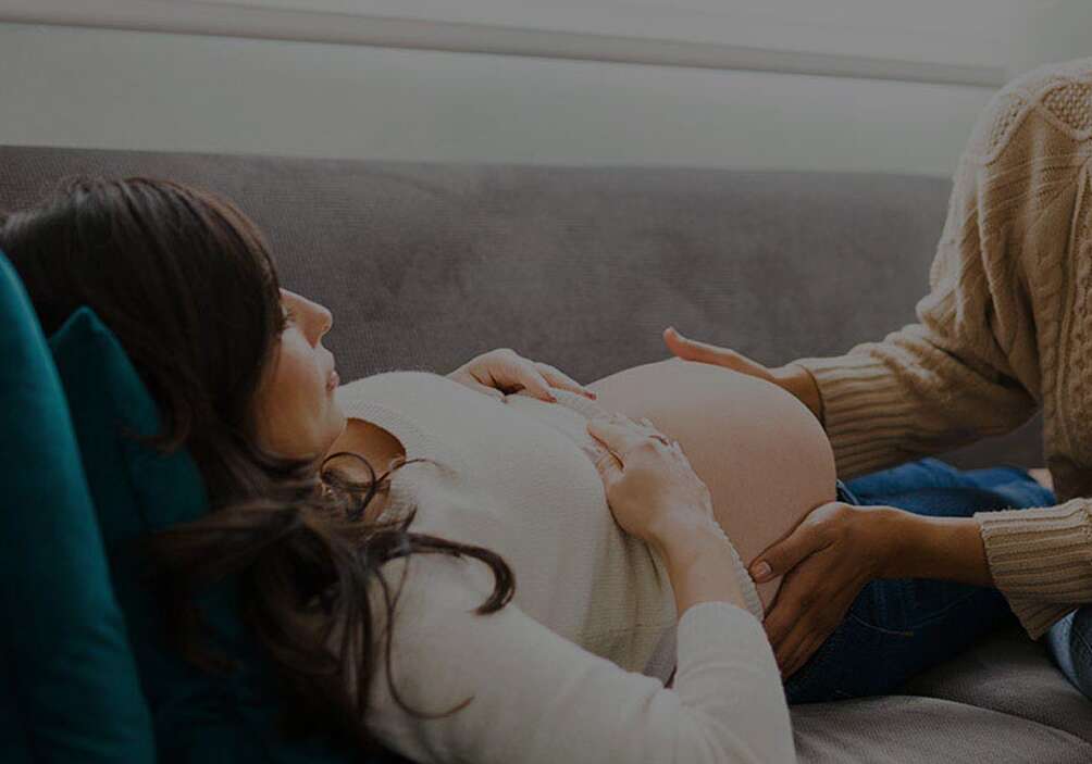 A pregnant woman resting with her hands on her belly